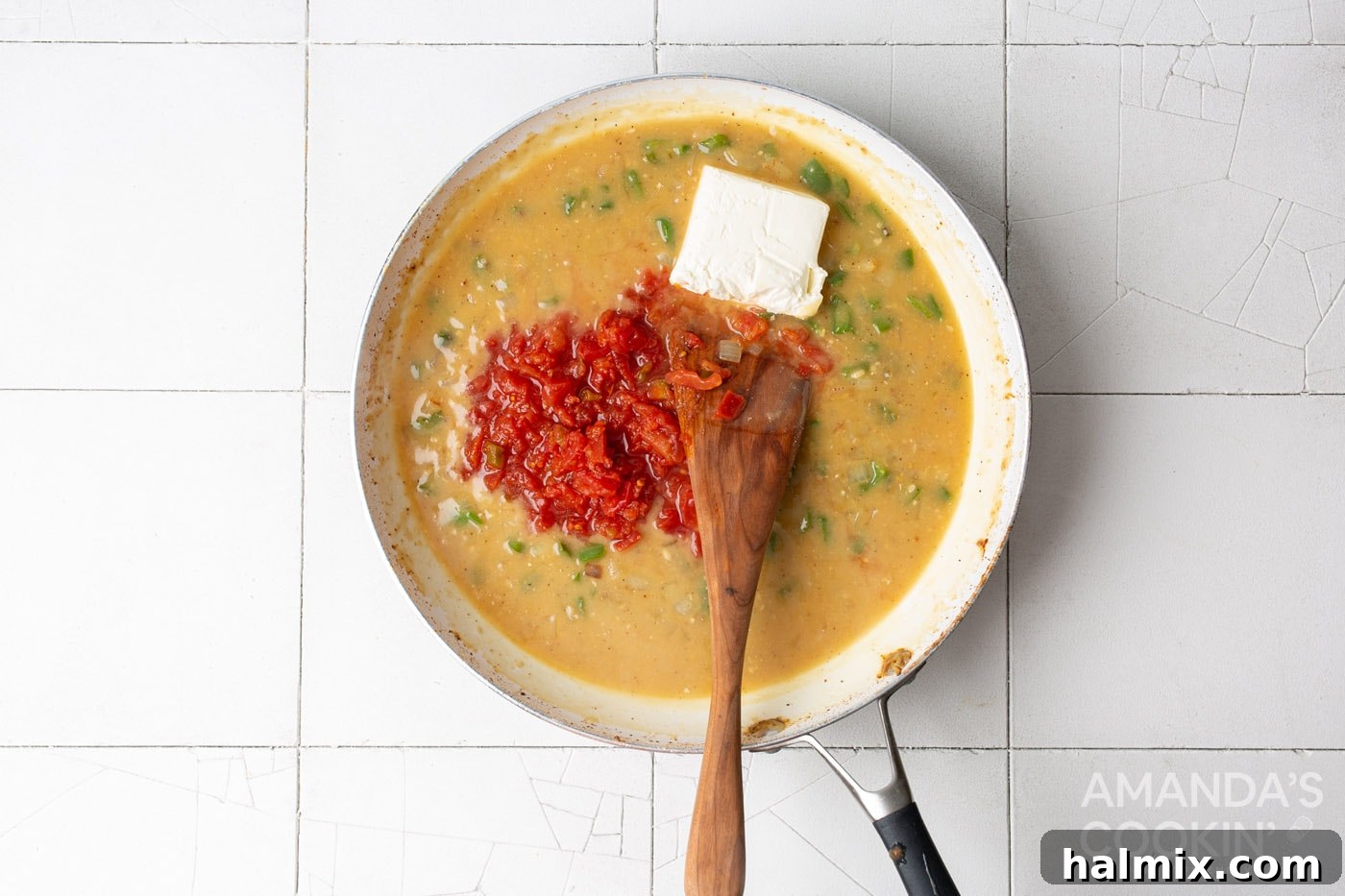 chicken broth, rotel tomatoes, and cream cheese simmering in a skillet to form a creamy sauce