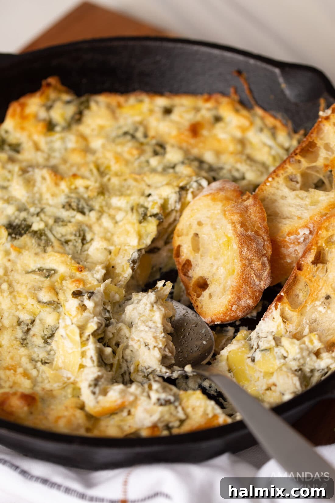 Irresistible Spinach Artichoke Dip 7 pan of Spinach Artichoke Dip with a spoon in it