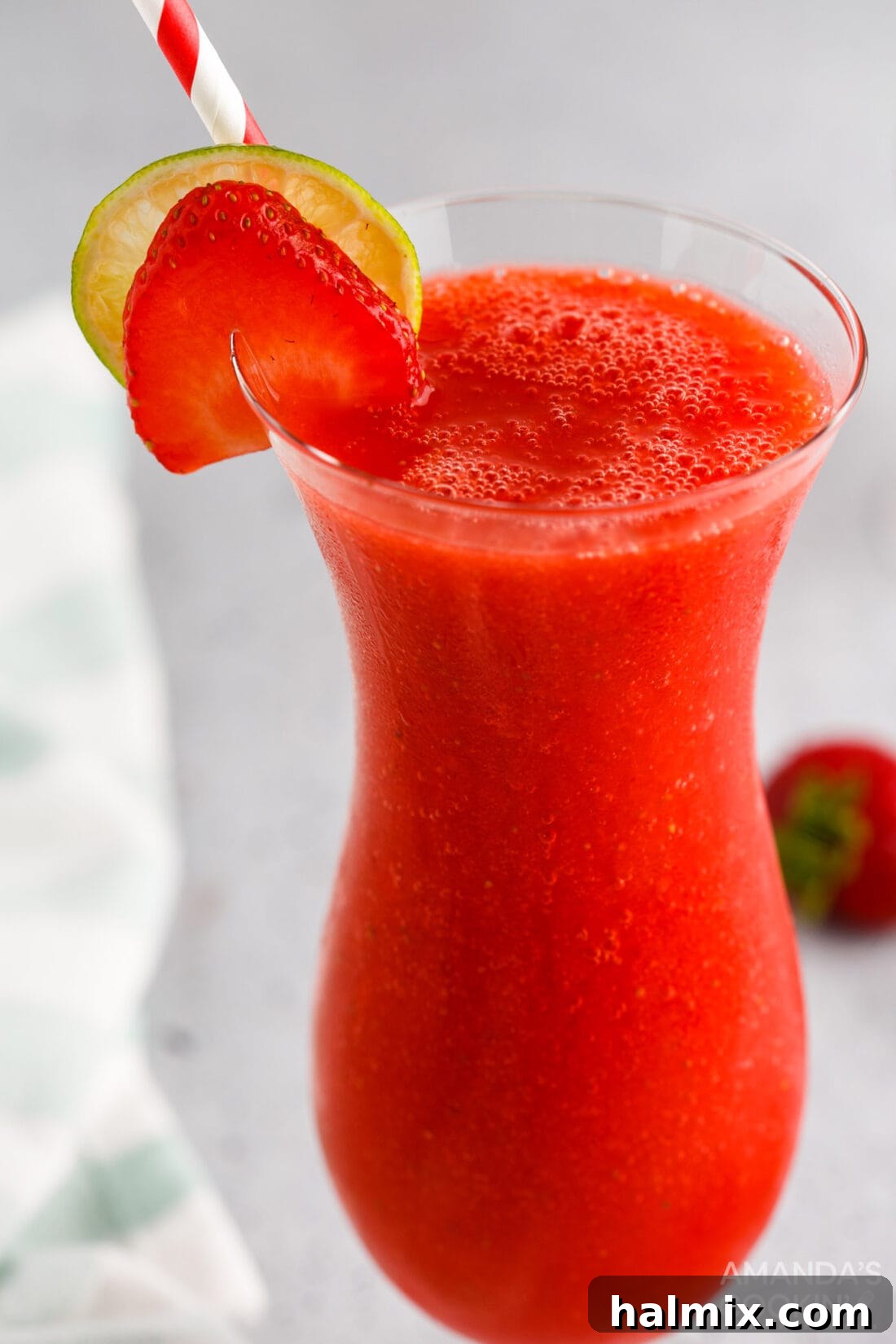 Vibrant Strawberry Daiquiri 3 Two Strawberry Daiquiris garnished with fresh strawberries and lime wedges.