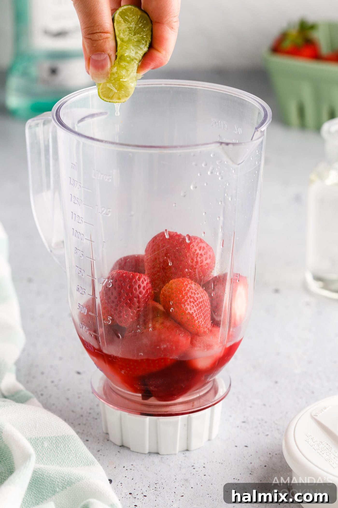 Vibrant Strawberry Daiquiri 6 Squeezing fresh lime juice directly into a blender filled with strawberry daiquiri ingredients.