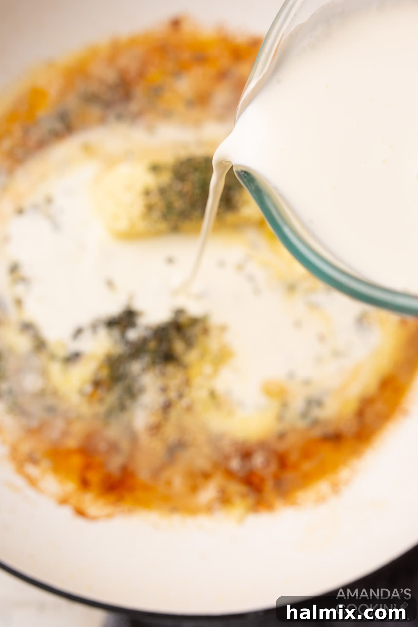 pouring heavy cream into skillet for alfredo sauce