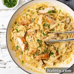 Chicken Alfredo in a serving dish with tongs