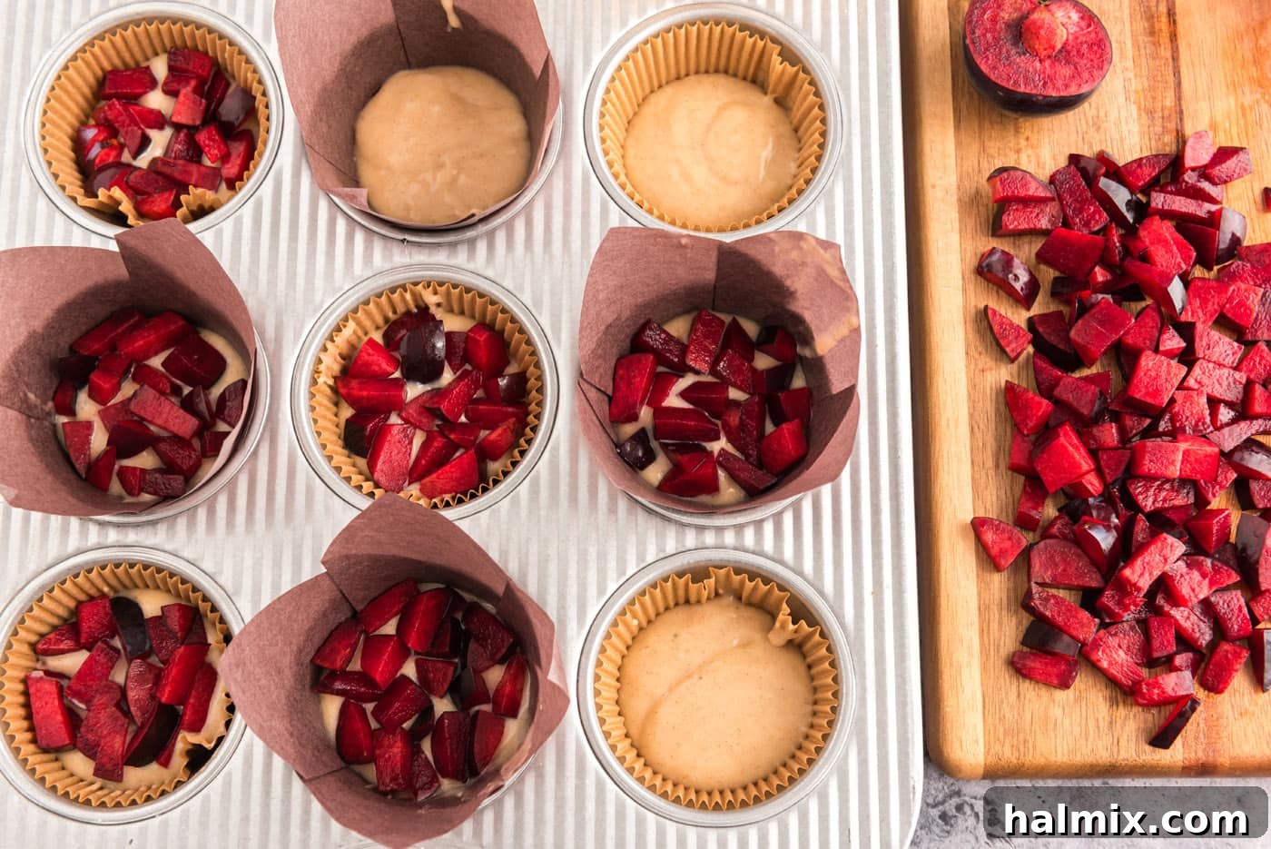 Golden Sugar Plum Muffins 13 Adding diced plums on top of the first layer of muffin batter in a muffin pan.