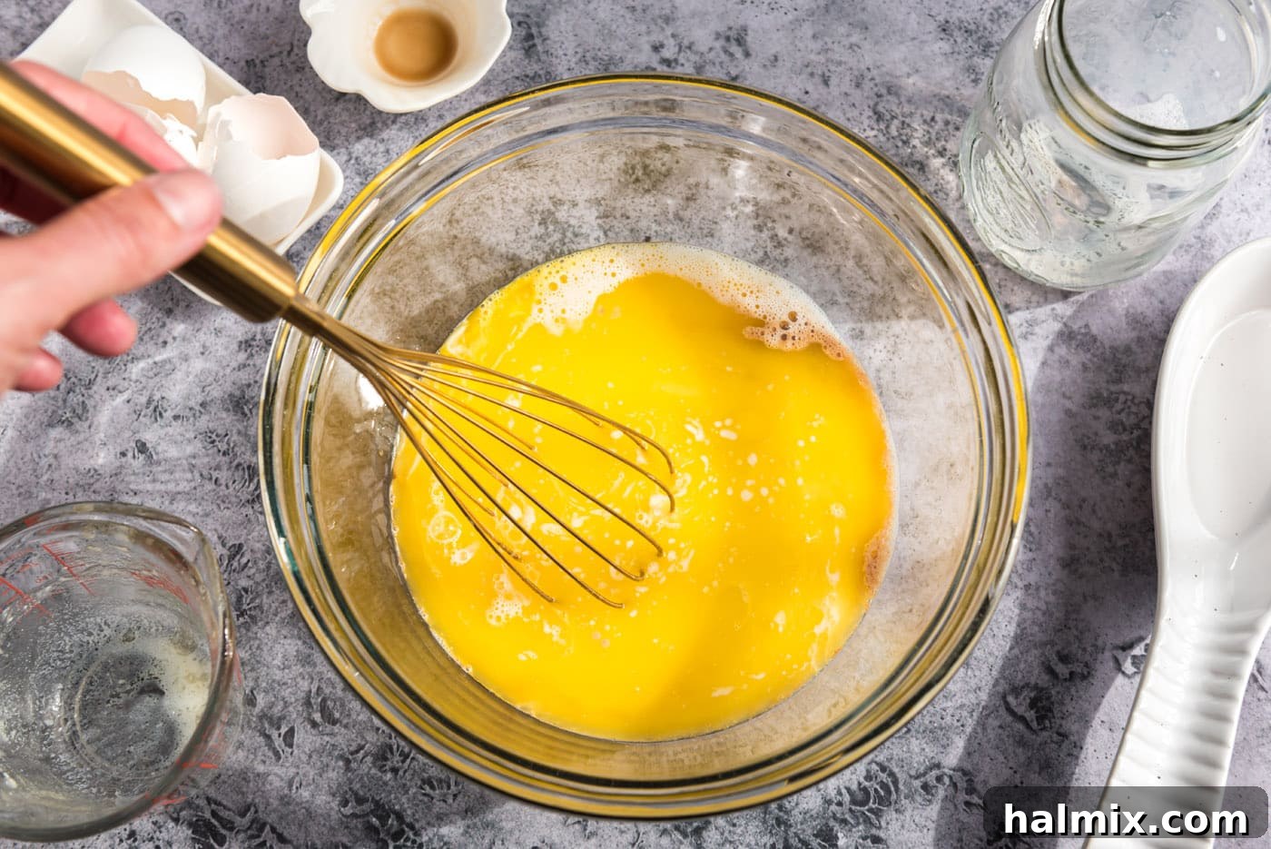 Golden Sugar Plum Muffins 7 A hand whisking the egg and milk mixture in a bowl, showing the liquids combining.