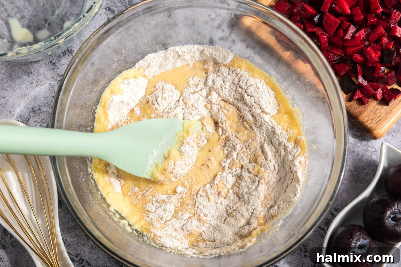 Golden Sugar Plum Muffins 10 A rubber spatula gently combining the wet and dry ingredients in a bowl, showing the muffin batter forming.