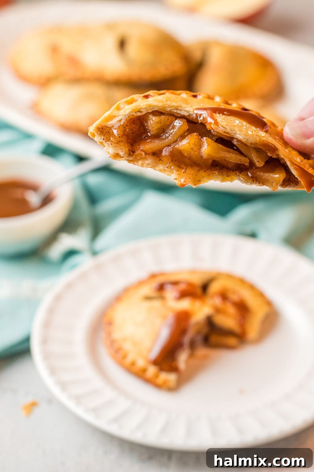 An apple hand pie cut in half, revealing the perfectly cooked, succulent apple filling nestled within a golden, flaky pastry crust.