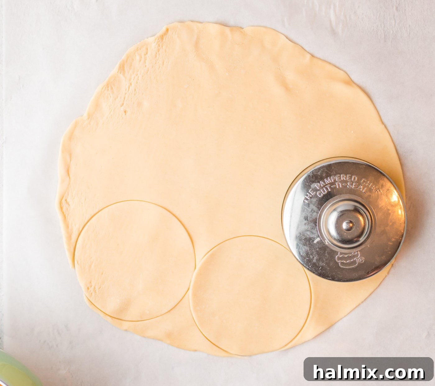 Pie crust circles being precisely cut out from a sheet of dough, ensuring consistent sizing for all hand pies.