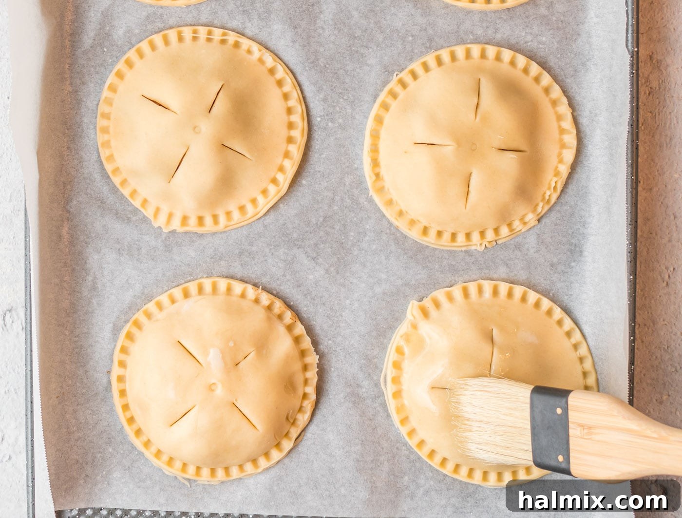 Edges of the hand pie being meticulously crimped with a fork, creating a strong seal and decorative finish.