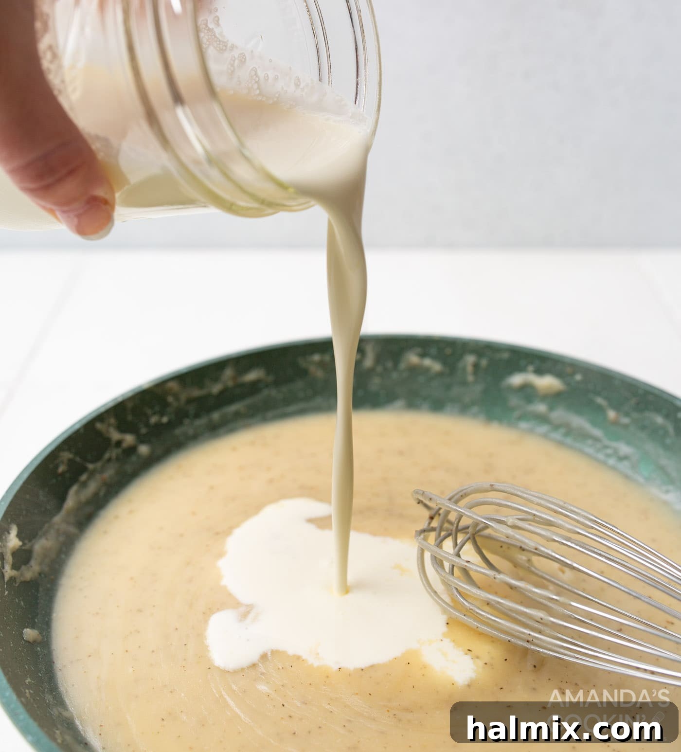 Velvety Creamy Chicken Soup 7 Pouring heavy cream into the cream of chicken soup base over a skillet, while whisking.
