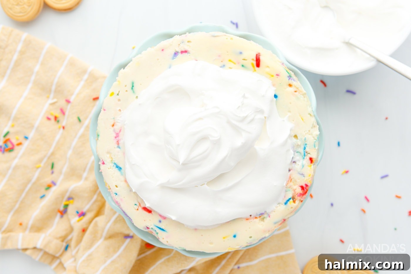 A dollop of whipped cream elegantly placed on top of a ready-to-serve funfetti cheesecake.