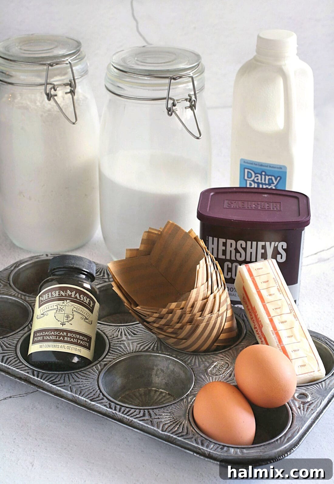 A selection of ingredients laid out for making Chocolate Peanut Butter Cupcakes, including flour, cocoa powder, sugar, butter, and peanut butter.