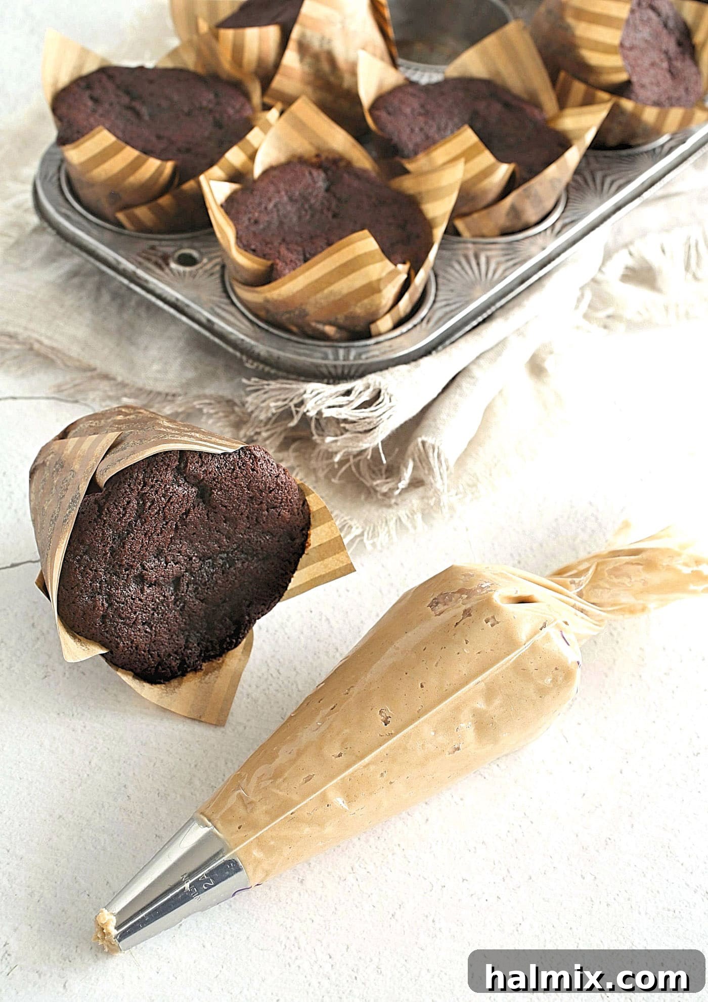 Peanut butter frosting being loaded into a piping bag with a large star tip.