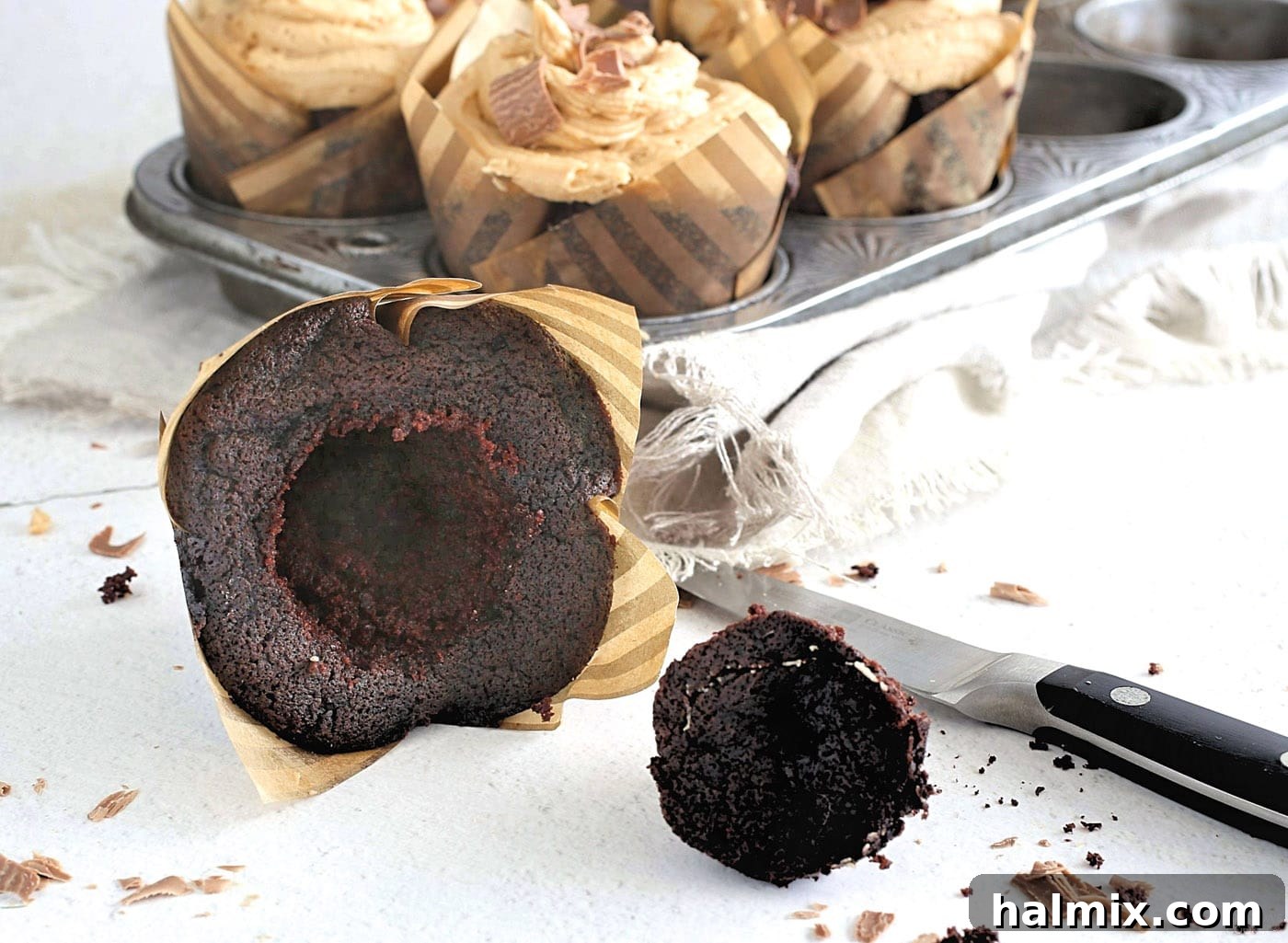 A chocolate cupcake with a core removed, ready to be filled with frosting.