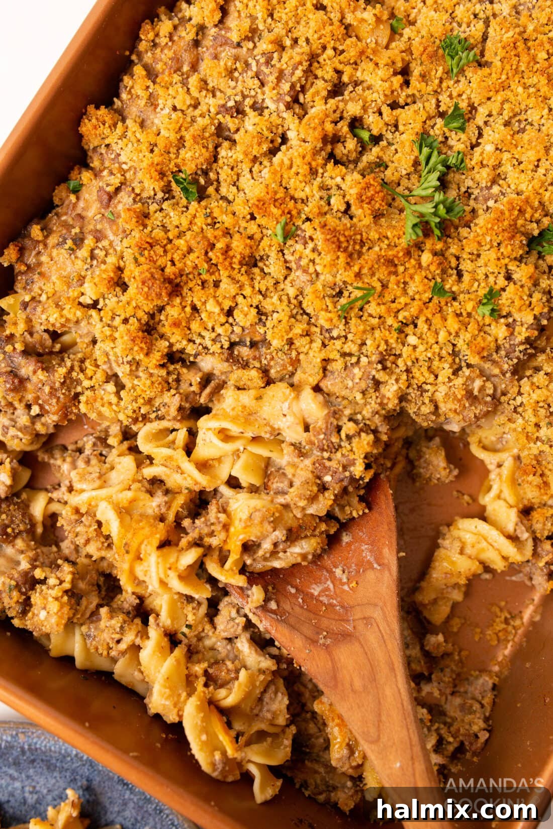 Creamy Beef Noodle Bake 2 A large pan of golden-brown Beef Stroganoff Casserole, with a serving spoon ready to dish out a portion, highlighting the creamy sauce and noodles.