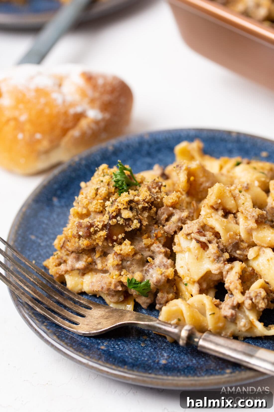 Creamy Beef Noodle Bake 3 A close-up shot of a serving of Beef Stroganoff Casserole on a white plate, showing the creamy sauce, chunks of beef, mushrooms, and egg noodles.