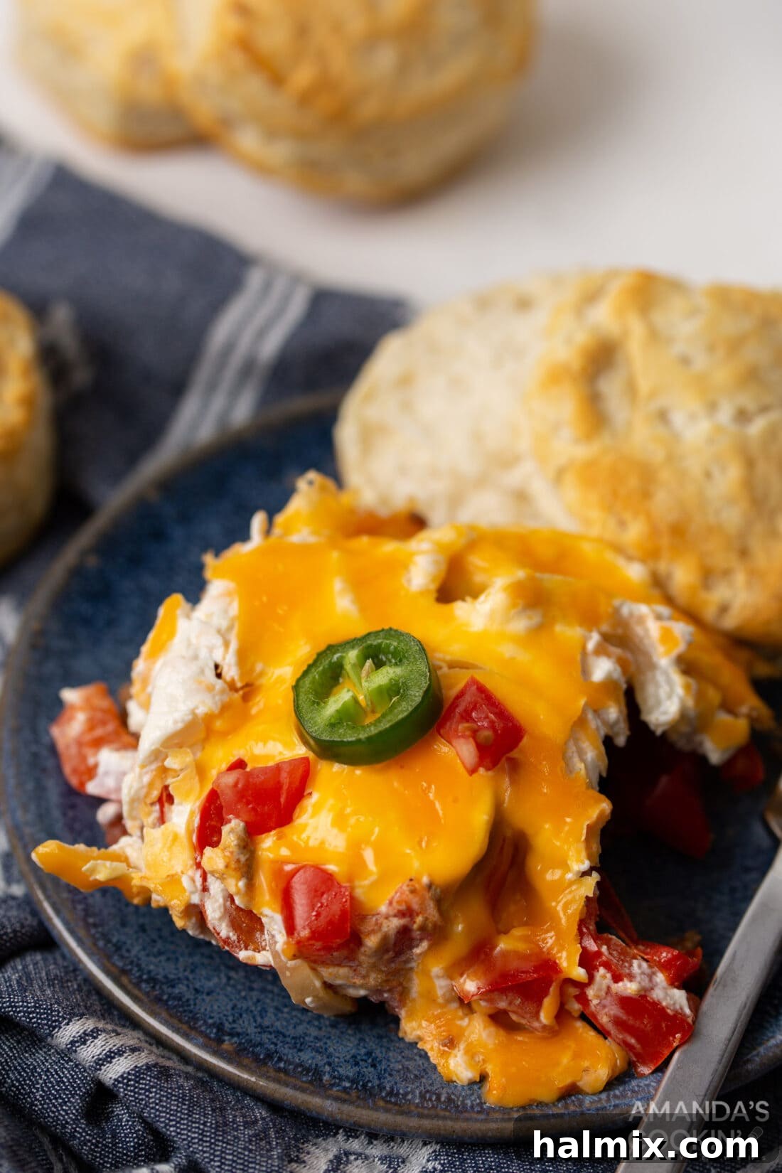 A serving of Crockpot John Wayne Casserole on a plate, garnished with fresh herbs and served alongside a warm biscuit.