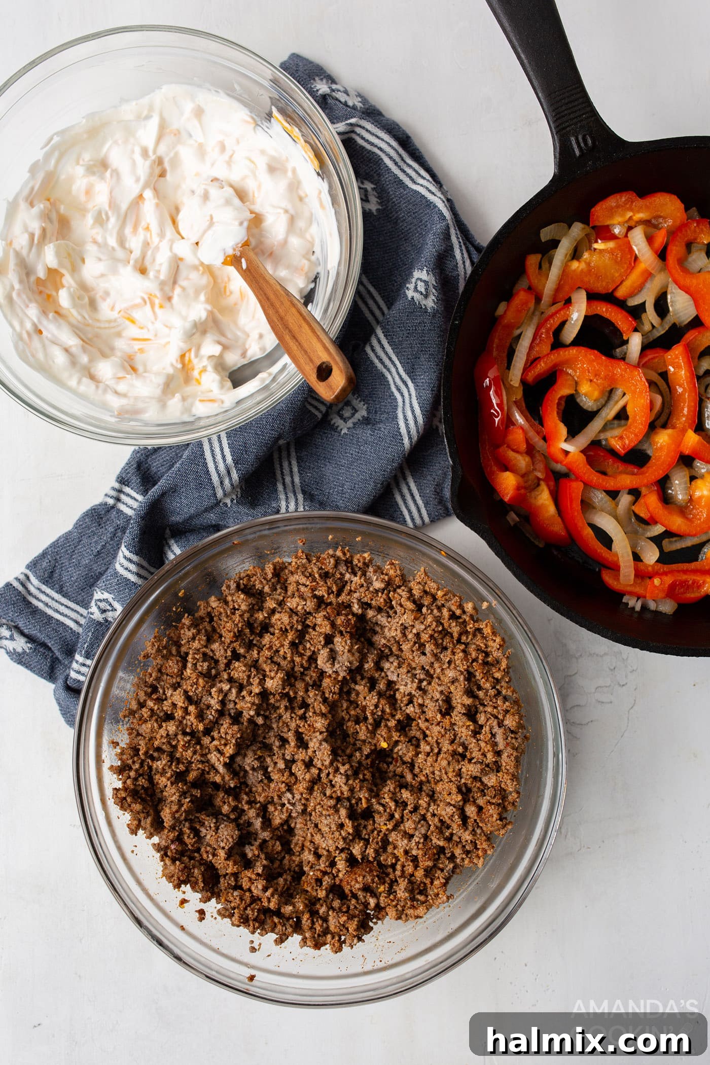 An overhead view showing the prepared ground beef, the creamy sour cream mixture, and the sautéed vegetables, ready for layering in the slow cooker.