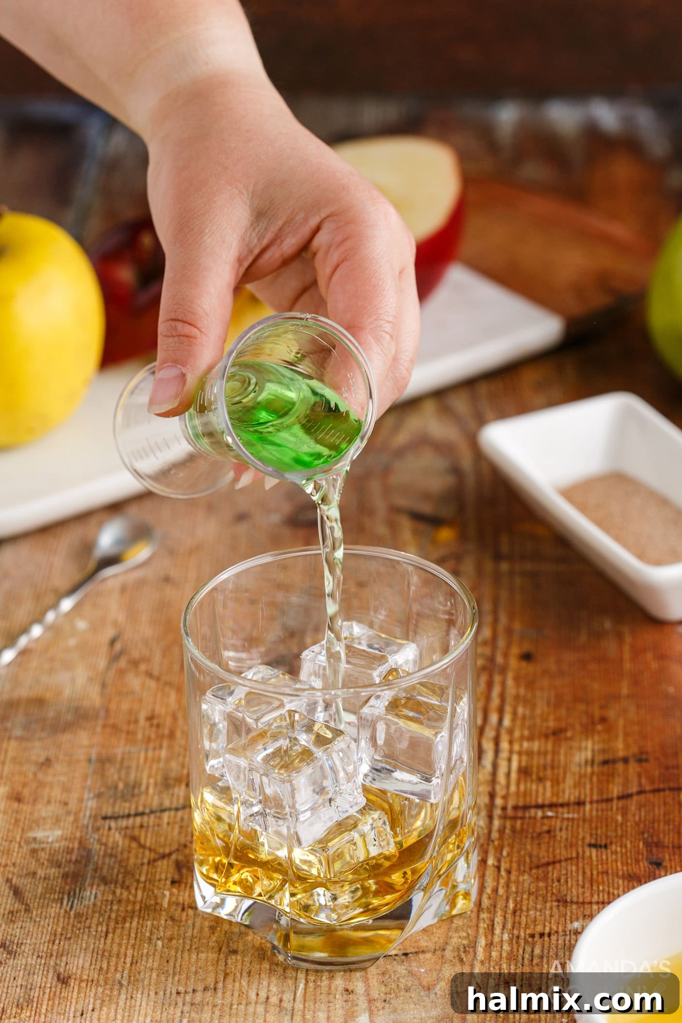 pouring apple pucker into a rock glass