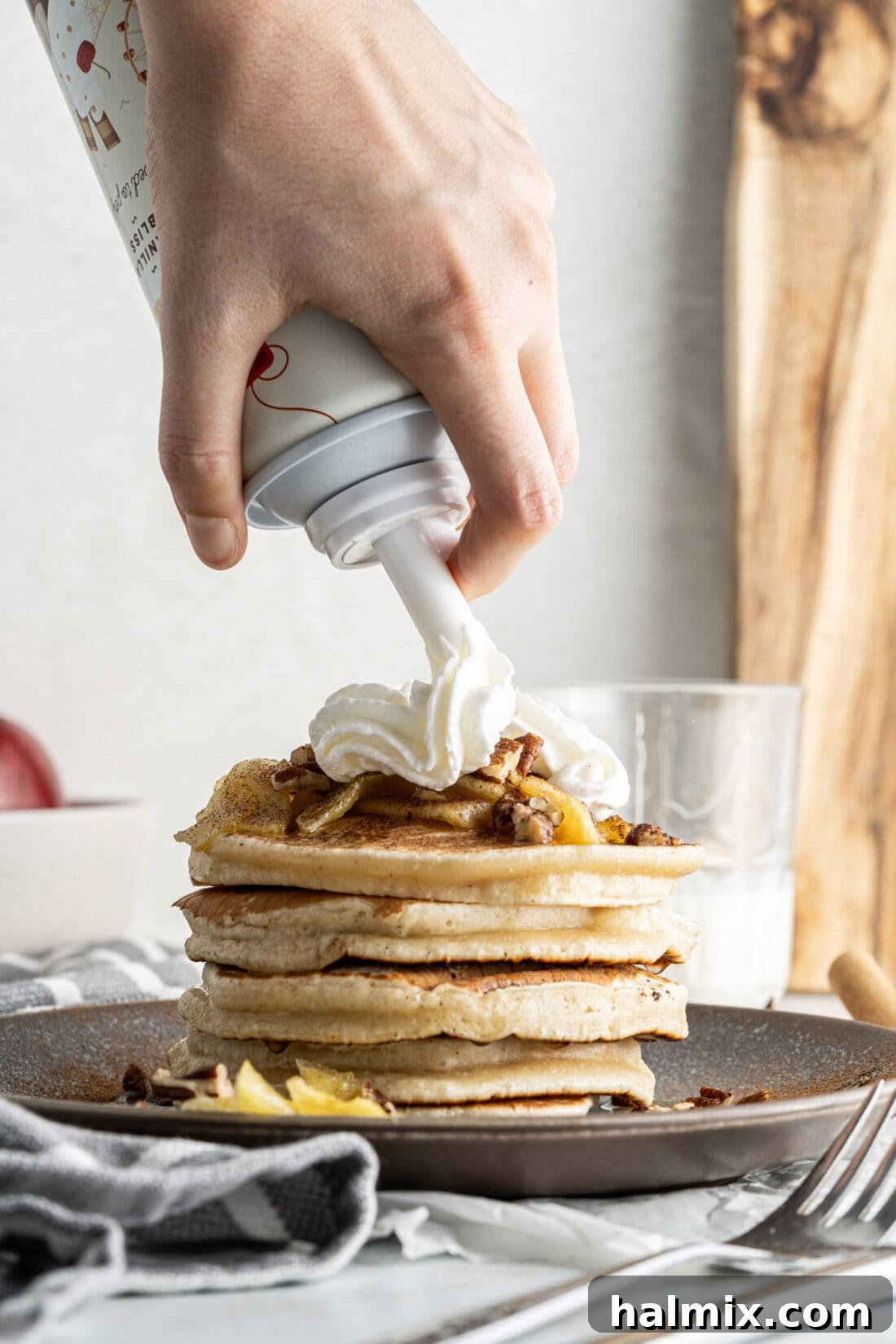 Apple Pie Pancakes 11 adding whipped cream to a stack of Apple Pancakes