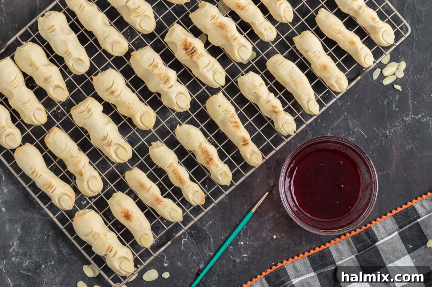 Hexed Hand Delights 14 Freshly baked Witch Finger Cookies, golden brown with sliced almond nails, cooled on a wire rack.