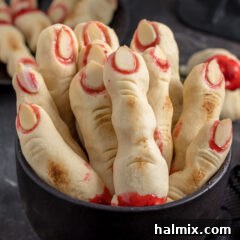 A close-up image of two finished Witch Finger Cookies, showcasing their creepy detail and vibrant jam 'blood'.