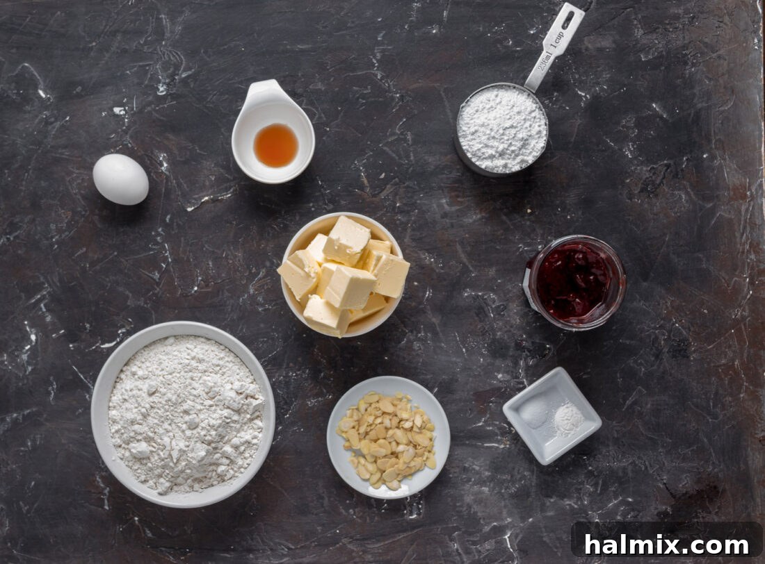 Hexed Hand Delights 4 A selection of ingredients neatly arranged on a counter, including butter, flour, sugar, eggs, vanilla, almonds, and strawberry jam, all ready for making Witch Finger Cookies.