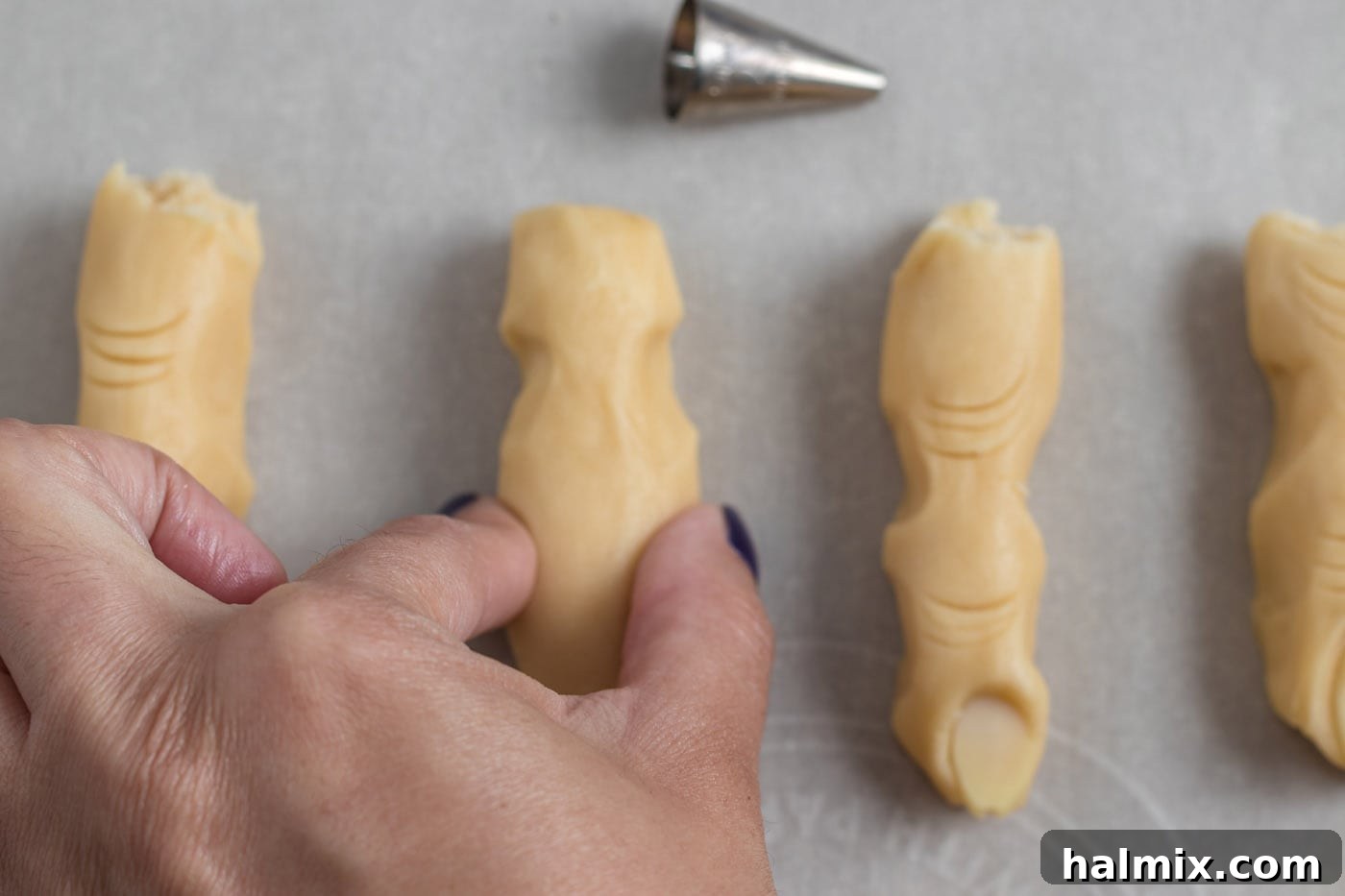 Hexed Hand Delights 10 Cookie dough cylinder with two distinct pinches, forming the nail bed and knuckle areas of a witch finger.