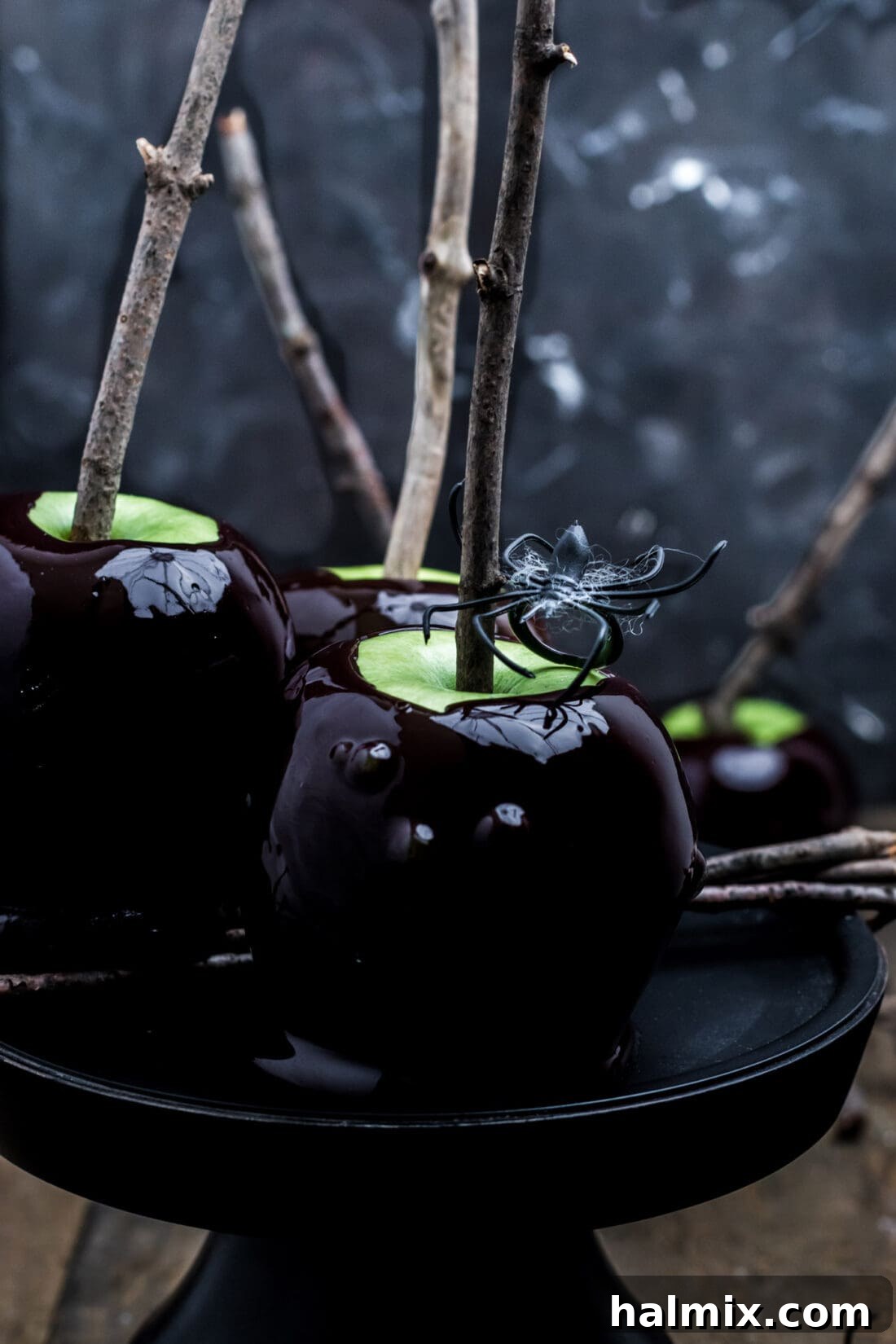 Glossy black Halloween candy apple on a dark background, evoking a spooky aesthetic.