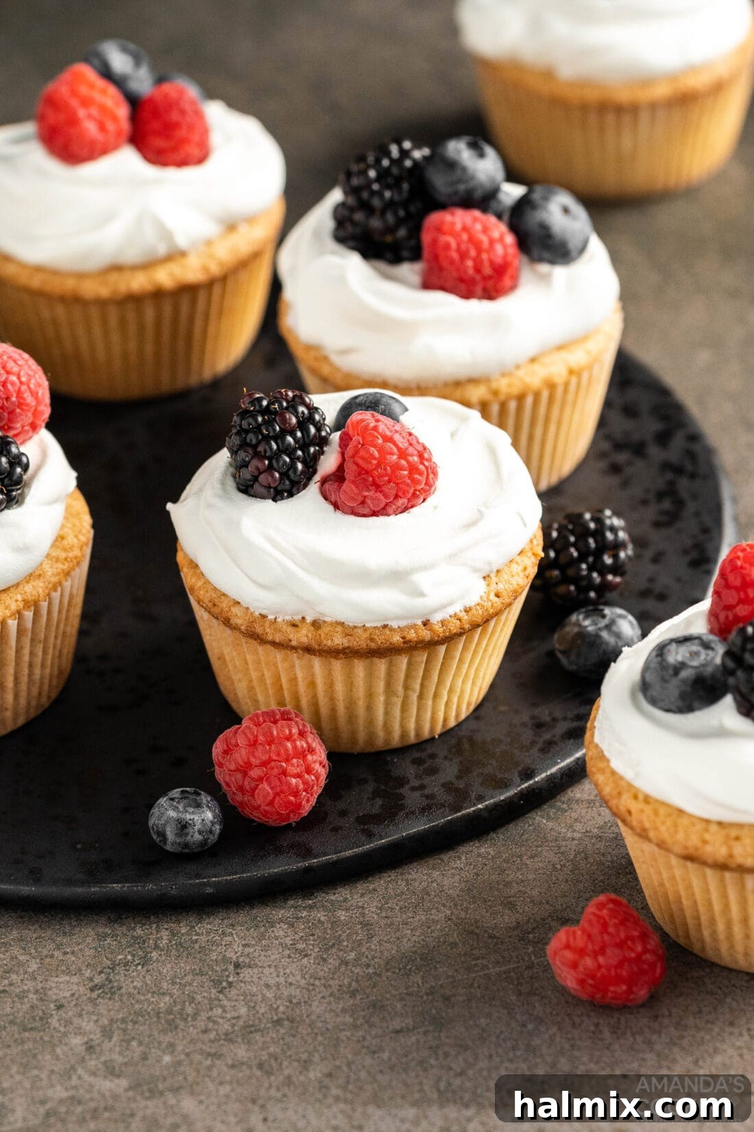 Pound Cake Minis 2 Delightful Pound Cake Cupcakes adorned with whipped cream and fresh berries, ready for serving on a plate