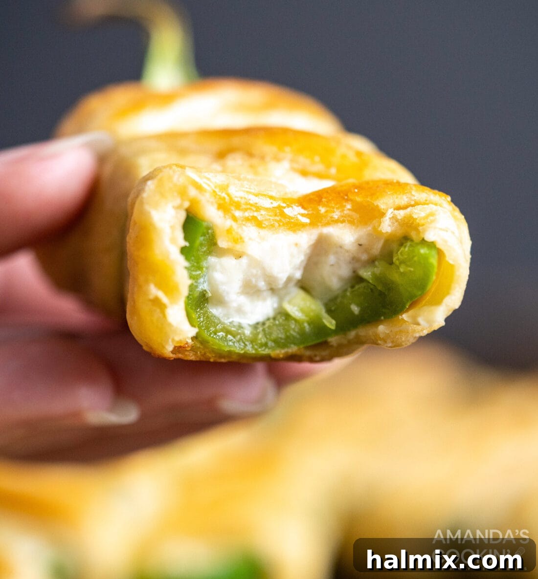 A Jalapeno Popper Mummy with a bite taken out, revealing the creamy cheese filling and fresh jalapeno
