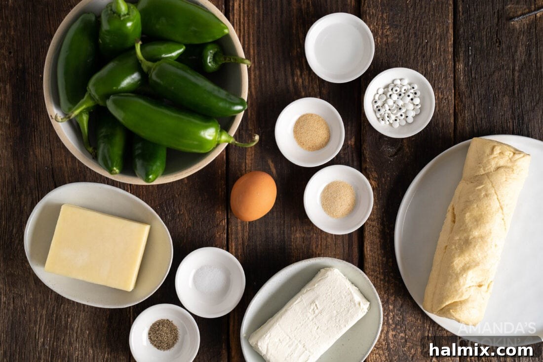 Ingredients for Jalapeno Popper Mummies laid out on a kitchen counter, including jalapenos, cheeses, and crescent rolls