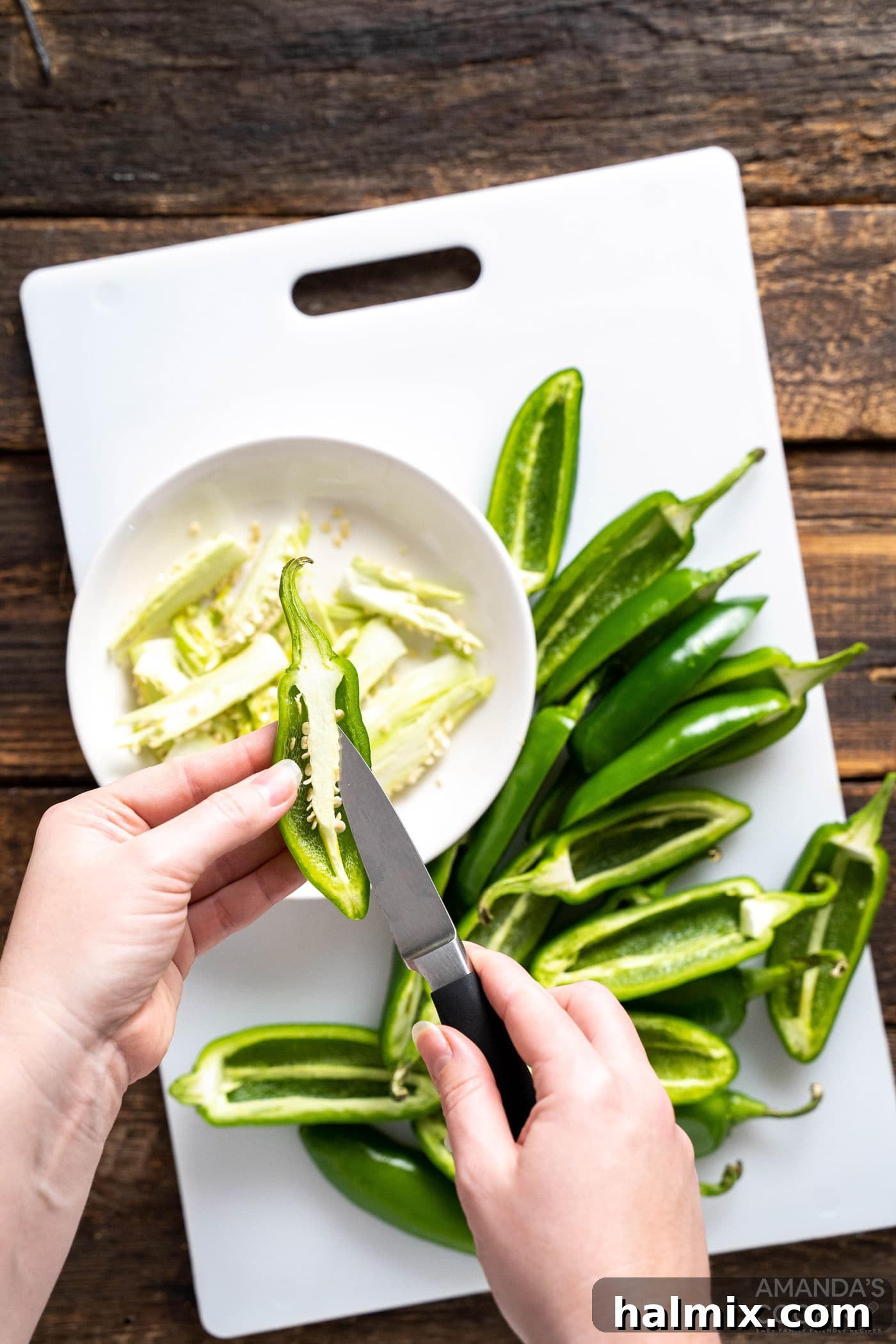 Removing seeds and ribs from jalapenos, illustrating the process of preparing the peppers for stuffing