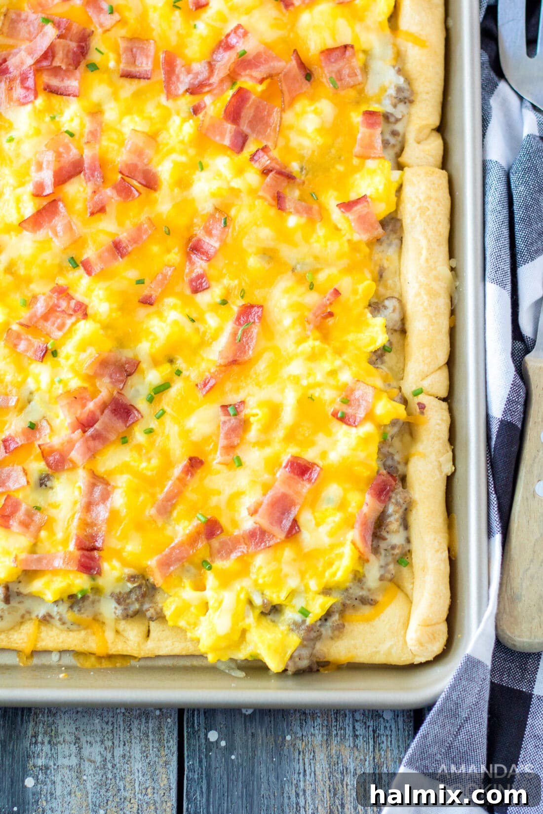 Overhead view of a freshly baked Sheet Pan Breakfast Pizza, topped with golden-brown sausage, fluffy scrambled eggs, crispy bacon, and melted cheese, ready to be sliced.