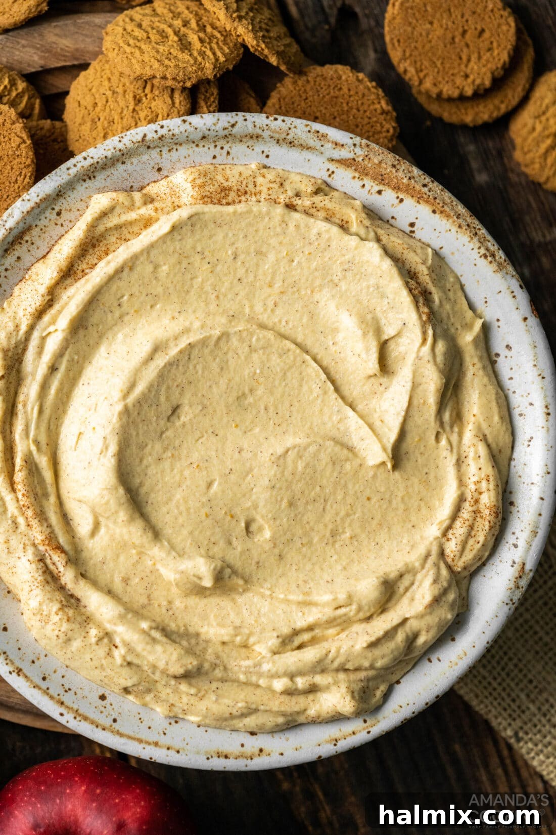 An inviting overhead view of the finished Pumpkin Pie Dip in a bowl, surrounded by a variety of colorful dippers like apples, strawberries, and cookies, suggesting a perfect fall snack or dessert spread.