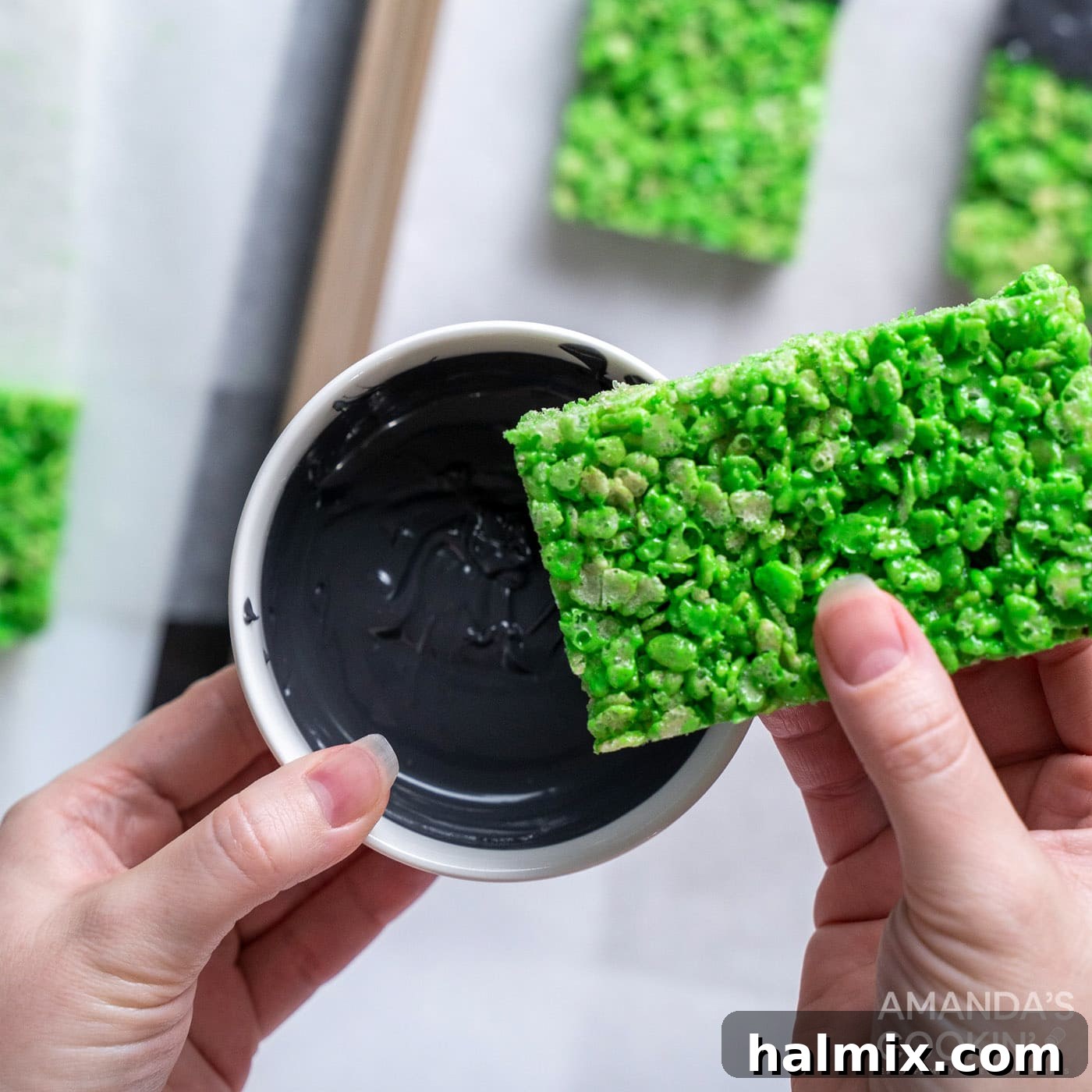 Frankenstein's Krispie Creations 13 Hand dipping green rice krispie treat into candy melts