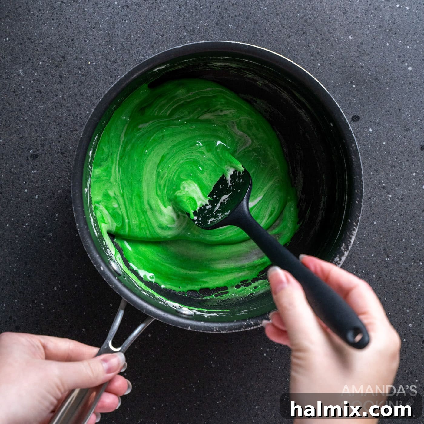 Frankenstein's Krispie Creations 7 Spoon stirring green food coloring into melted marshmallows