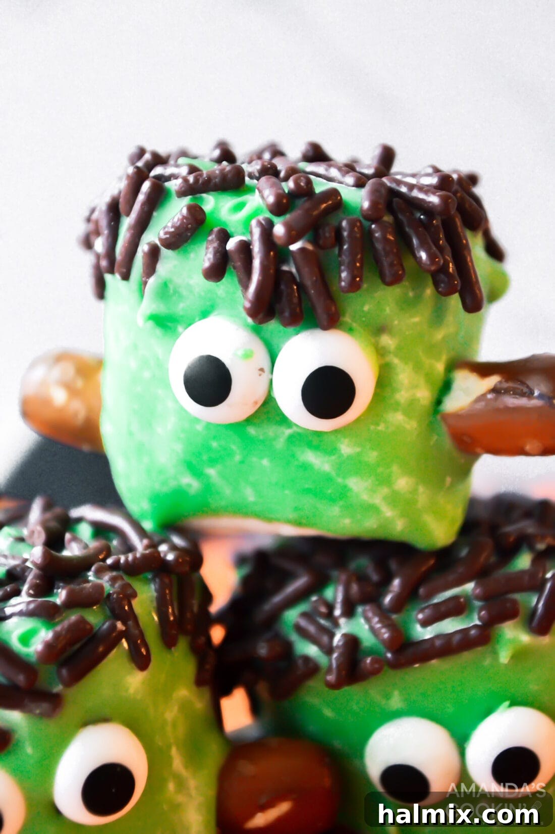 Close up photo of stacked Marshmallow Frankensteins with candy eyes and pretzel bolts for a fun Halloween treat.