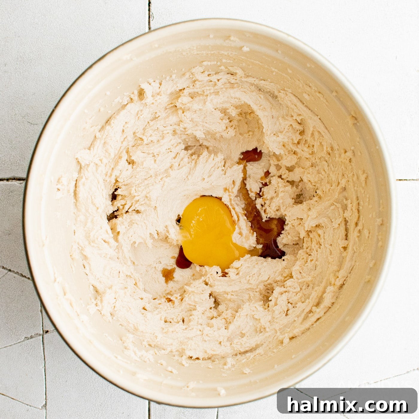 egg yolk in mixing bowl with butter and sugar mixture, ready to be blended.