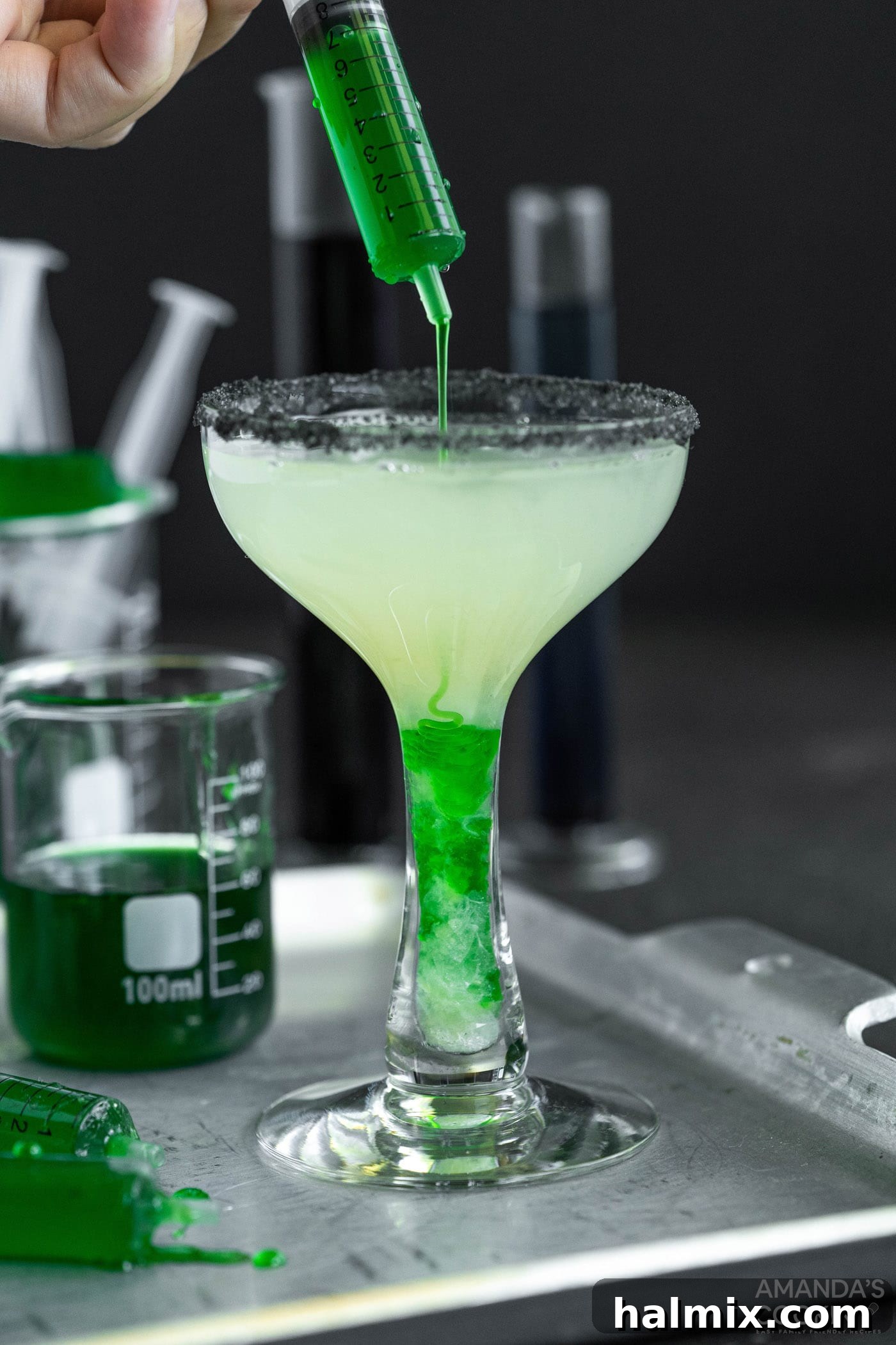 A close-up of a Frankenstein Margarita with green goo being added to the cocktail, enhancing its spooky appearance.