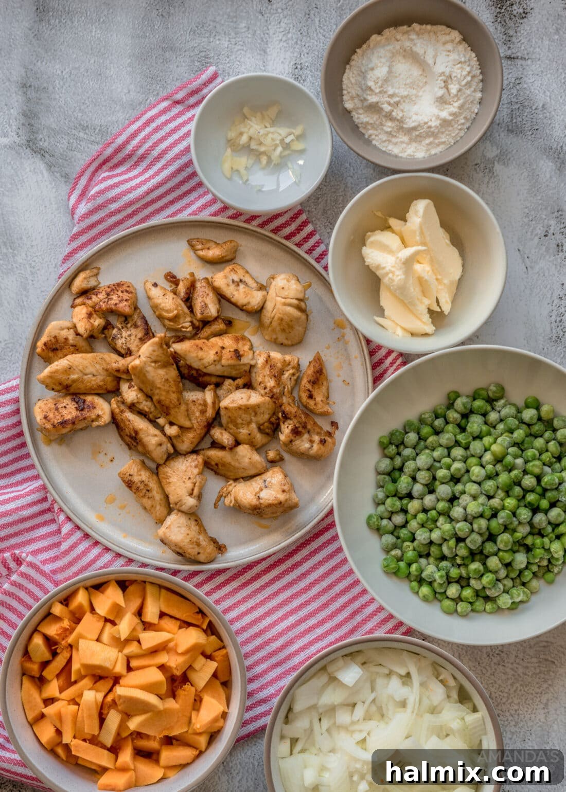 An array of fresh ingredients including pumpkin, chicken, peas, and pastry dough for making pot pie