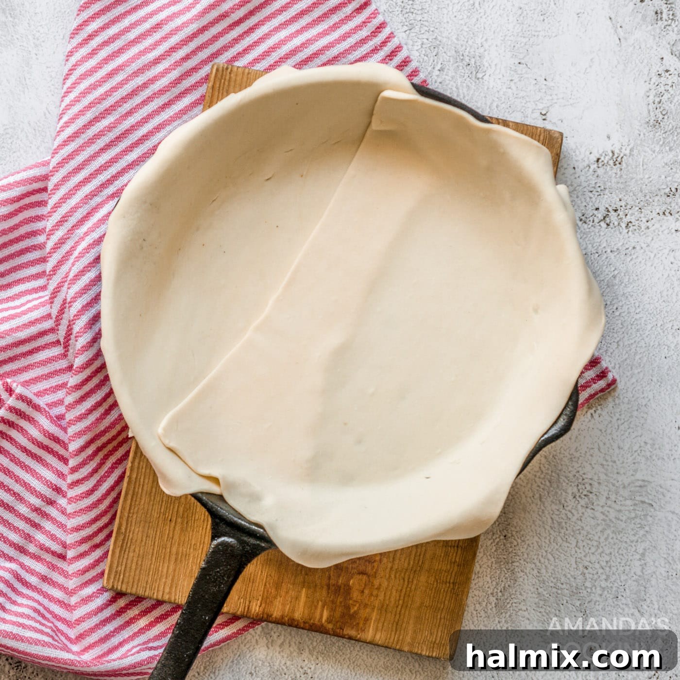 Delicate puff pastry expertly lining a sturdy cast iron skillet, awaiting the rich filling