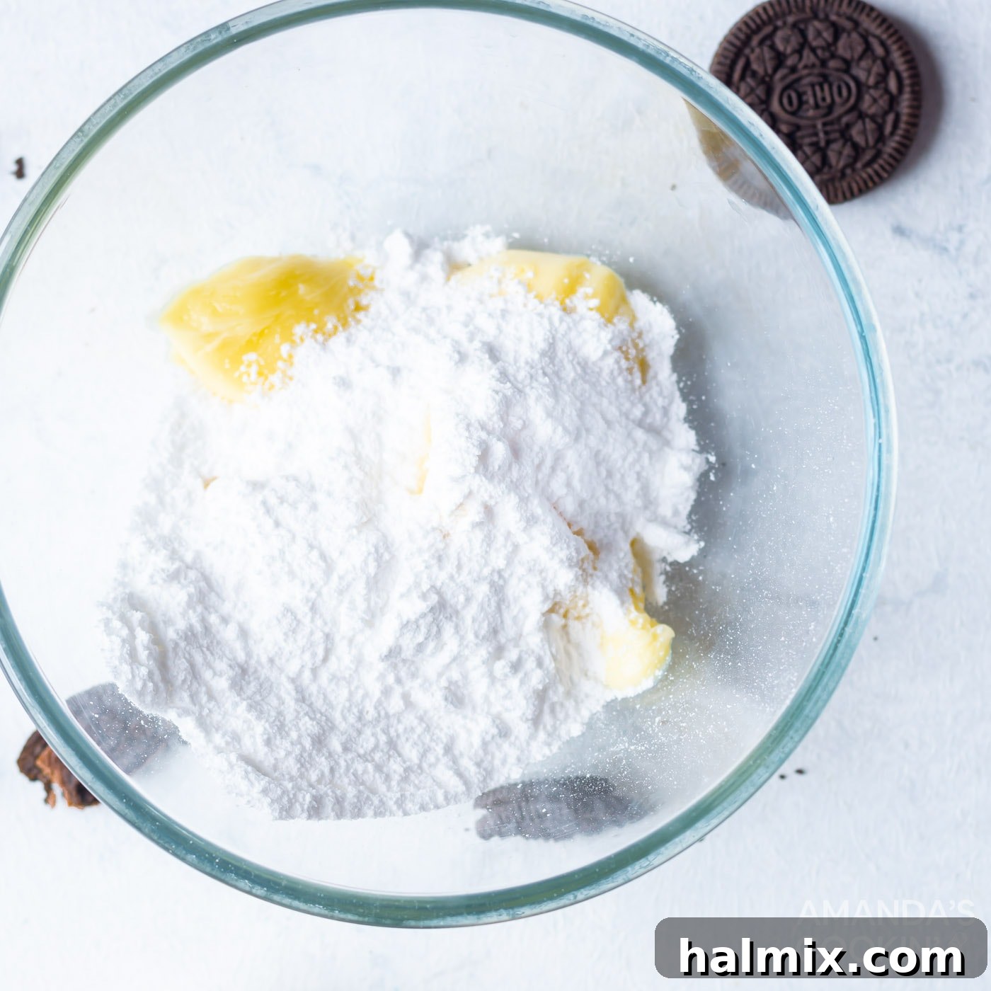 Softened butter in a mixing bowl is being combined with powdered sugar in batches, ready to be whipped into fluffy buttercream frosting.