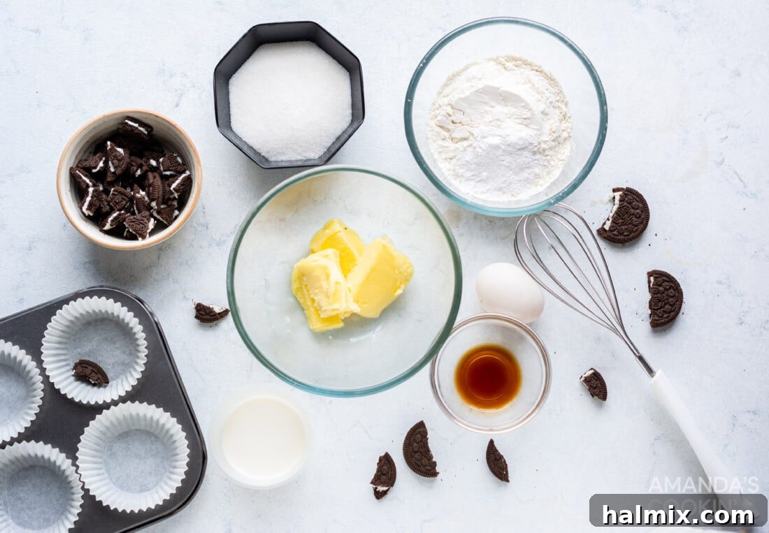 A selection of ingredients for making Oreo Cupcakes, including flour, sugar, butter, eggs, milk, vanilla extract, and several packages of Oreo cookies.