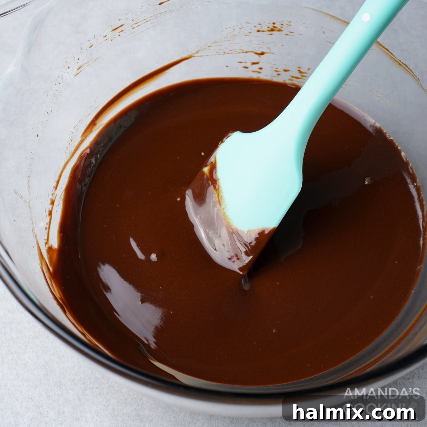 Melted chocolate and butter in a bowl with a rubber spatula