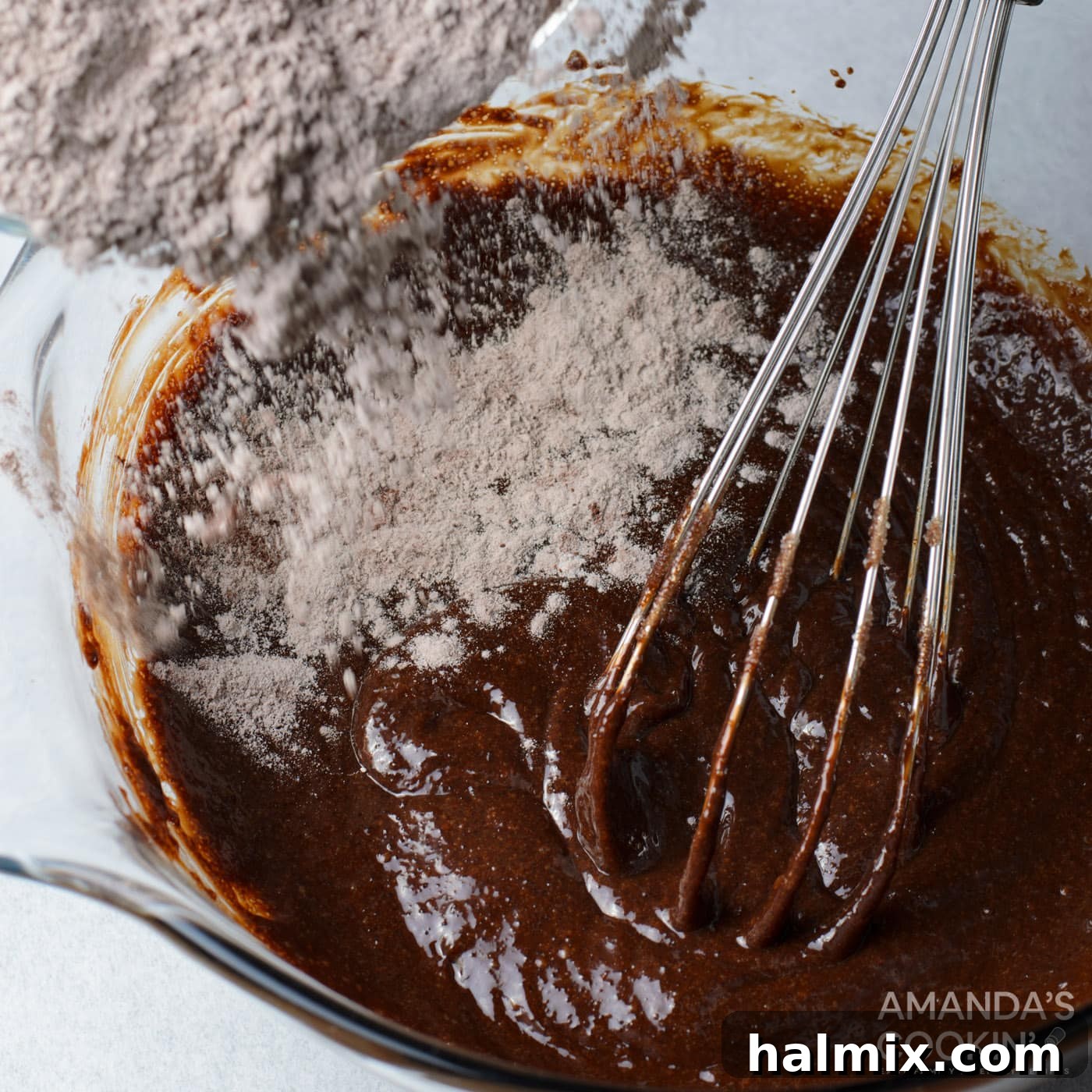 Dry ingredients being folded into the brownie batter with a whisk