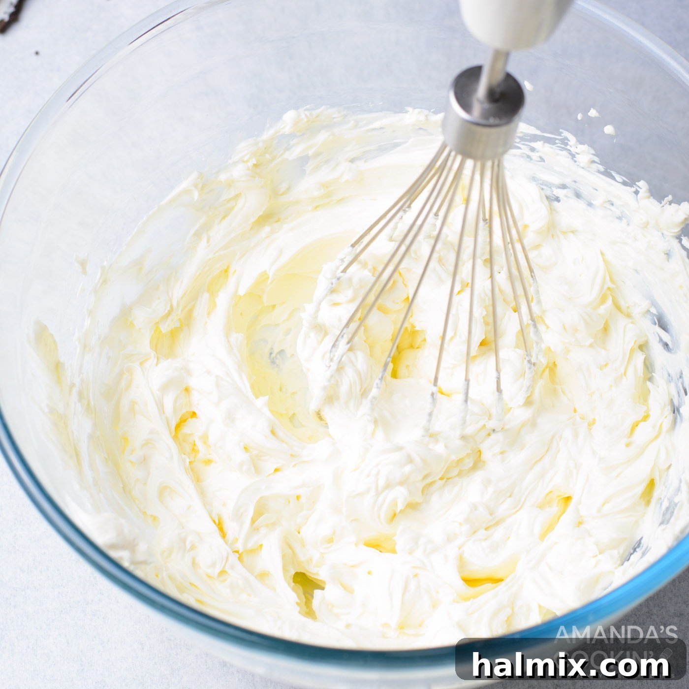 Cream cheese being mixed until fluffy for the cheesecake layer