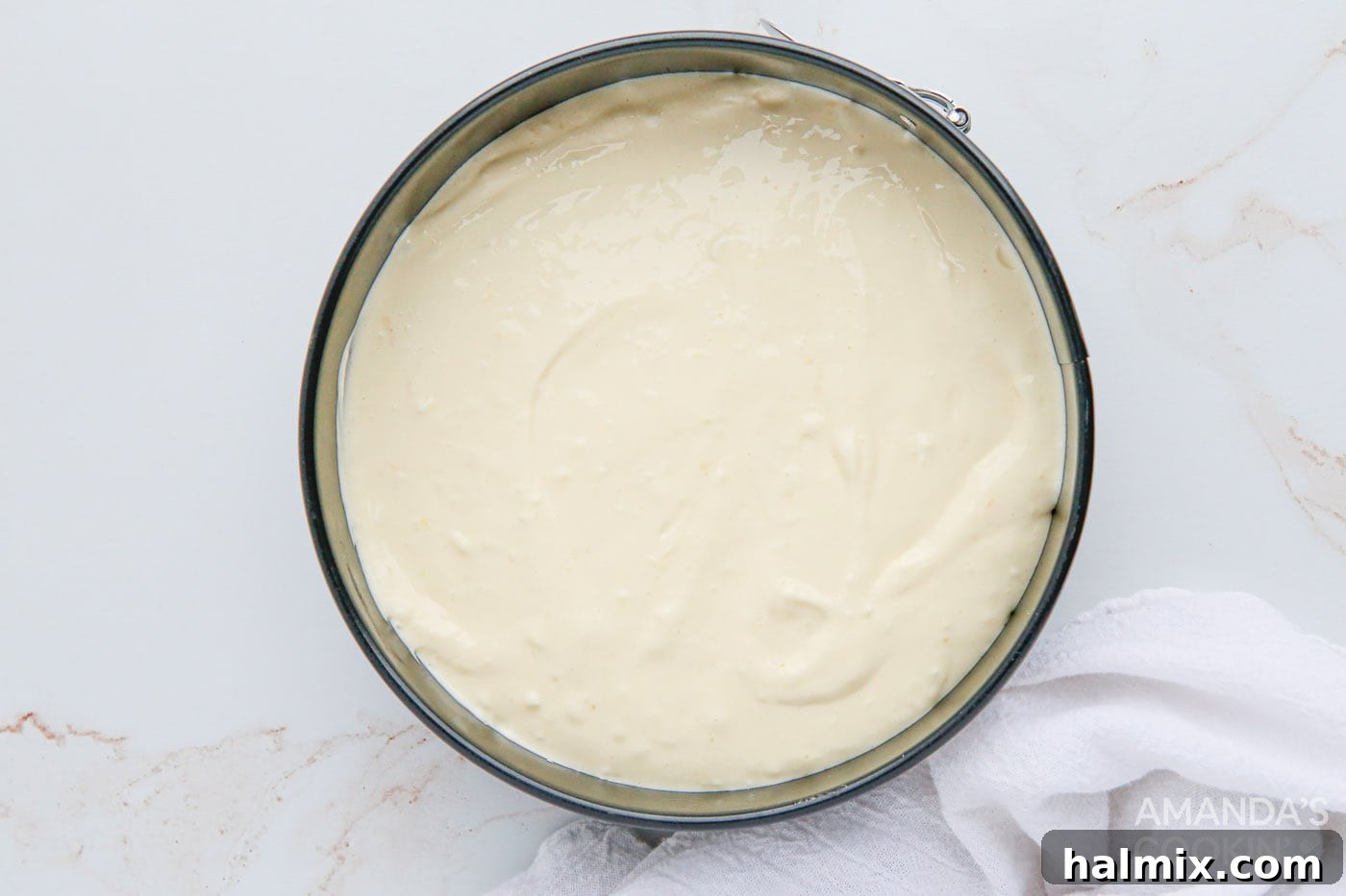 The top of the lemon cheesecake is smoothed with a spatula in the springform pan before wrapping for the Instant Pot.