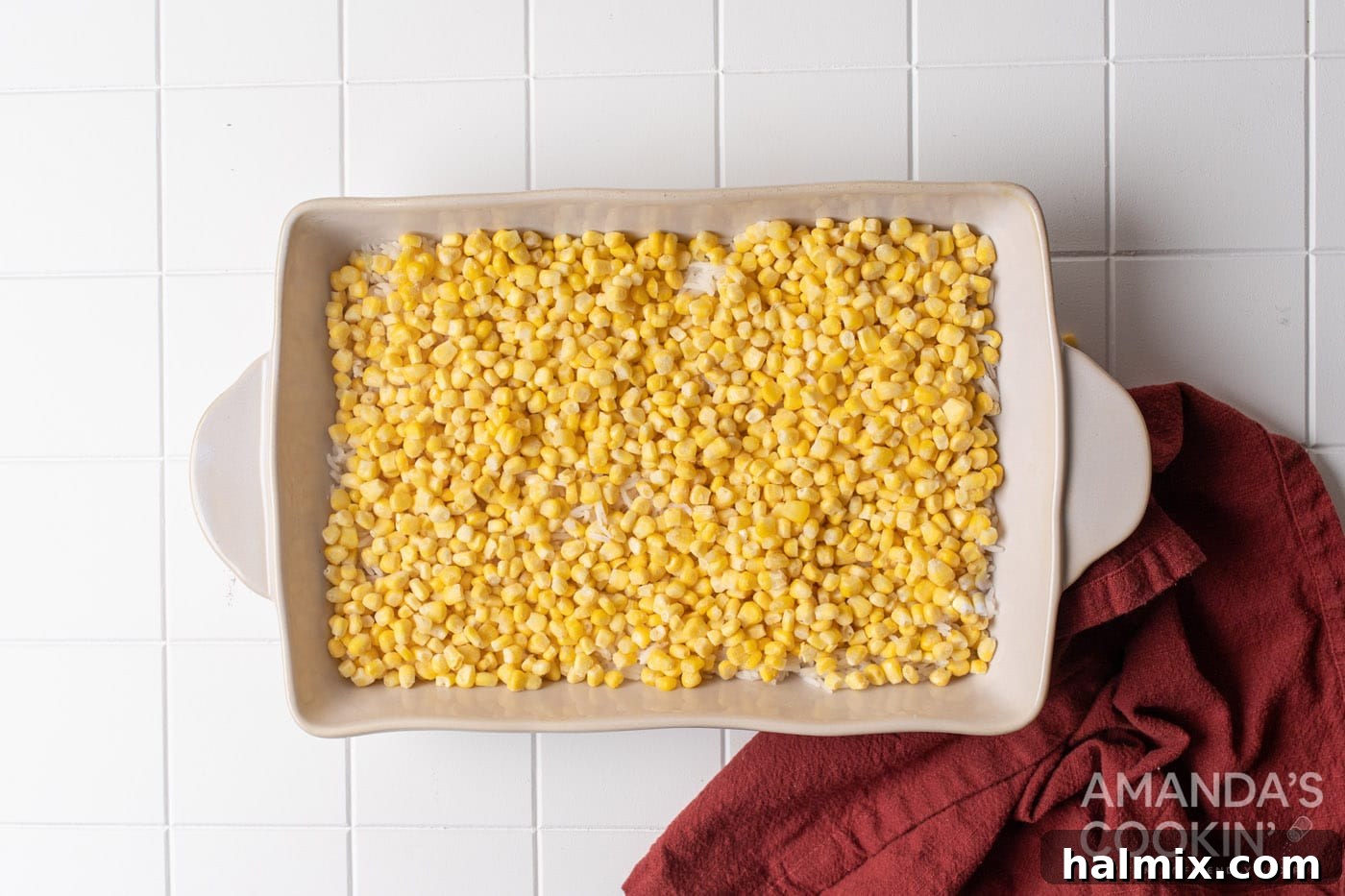 corn is spread on top of the rice layer in the casserole dish