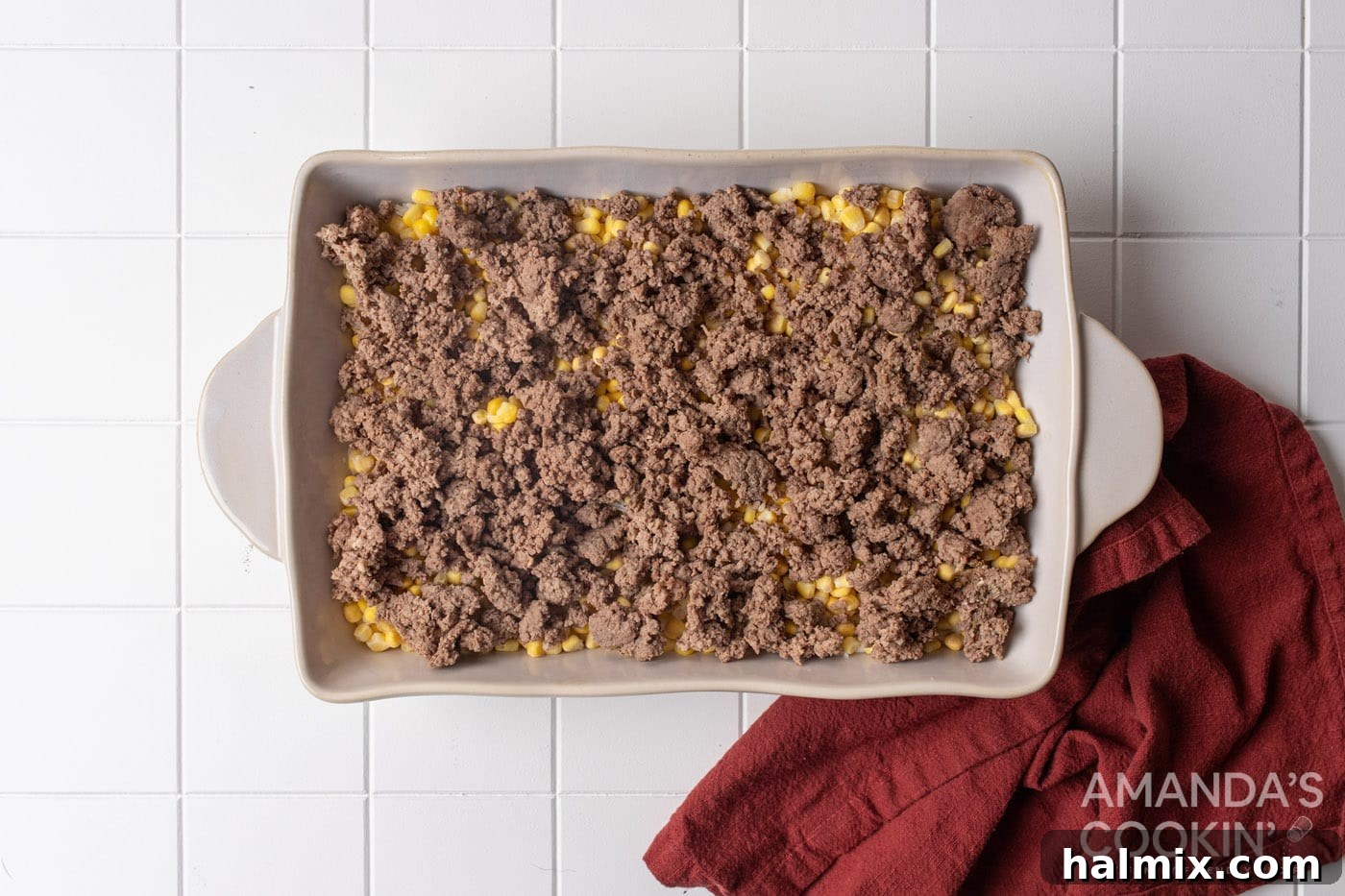cooked ground beef is added over the corn and rice layers in a dish