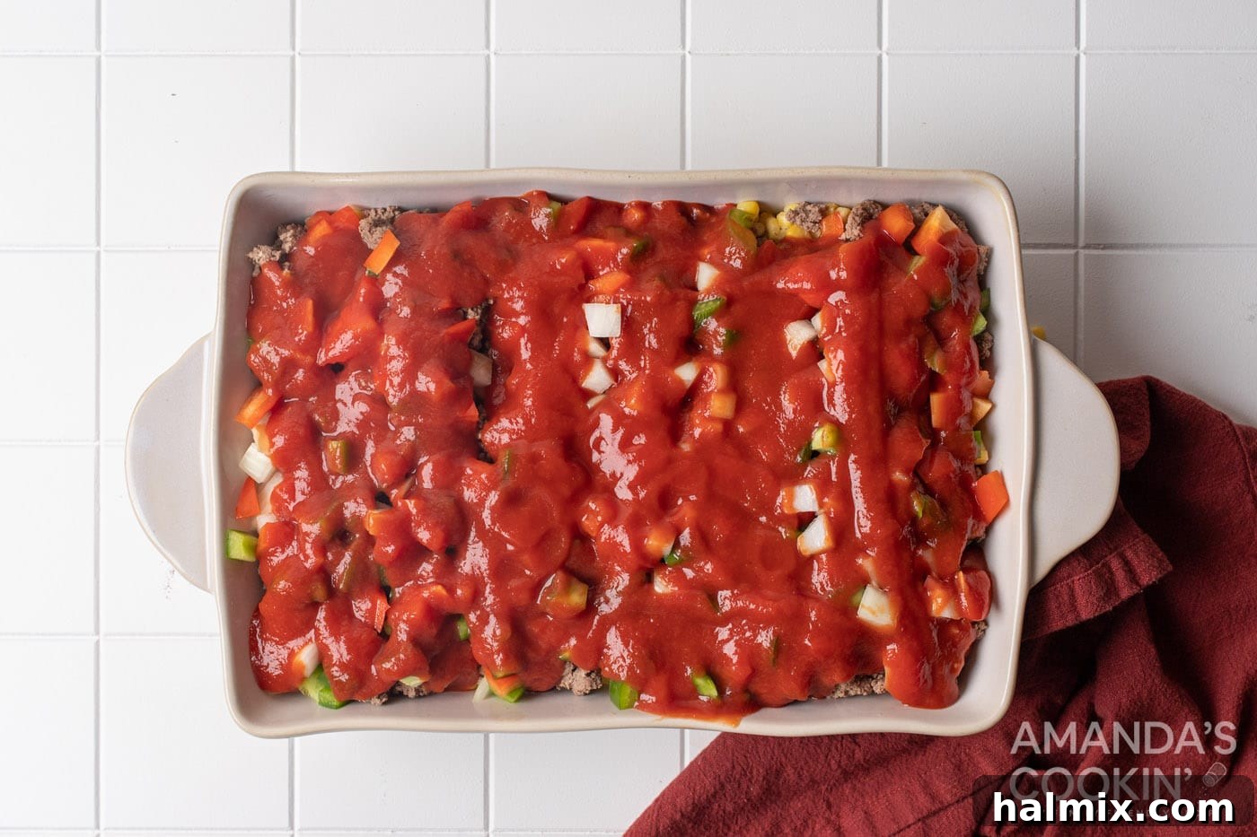 pasta sauce is poured evenly over the veggie layer in the baking dish